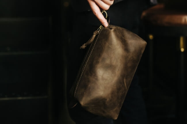 Hand holding a Kruk Garage leather Travel Pouch, a compact and elegant accessory for organized travel.
